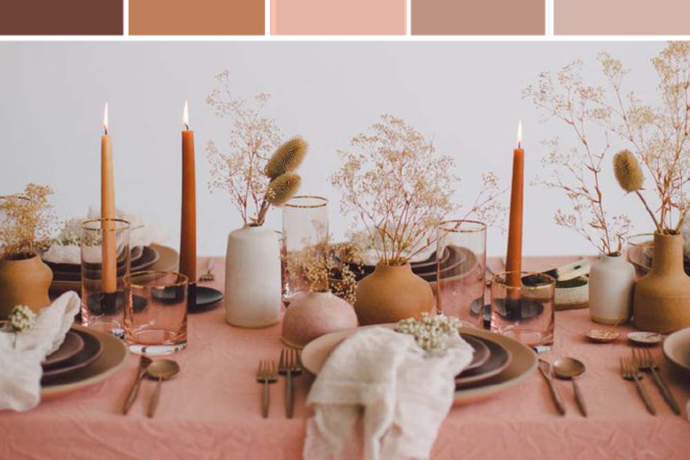a table decorated in prairie grass centerpieces, tall ochre candles and blush pink tablecloth