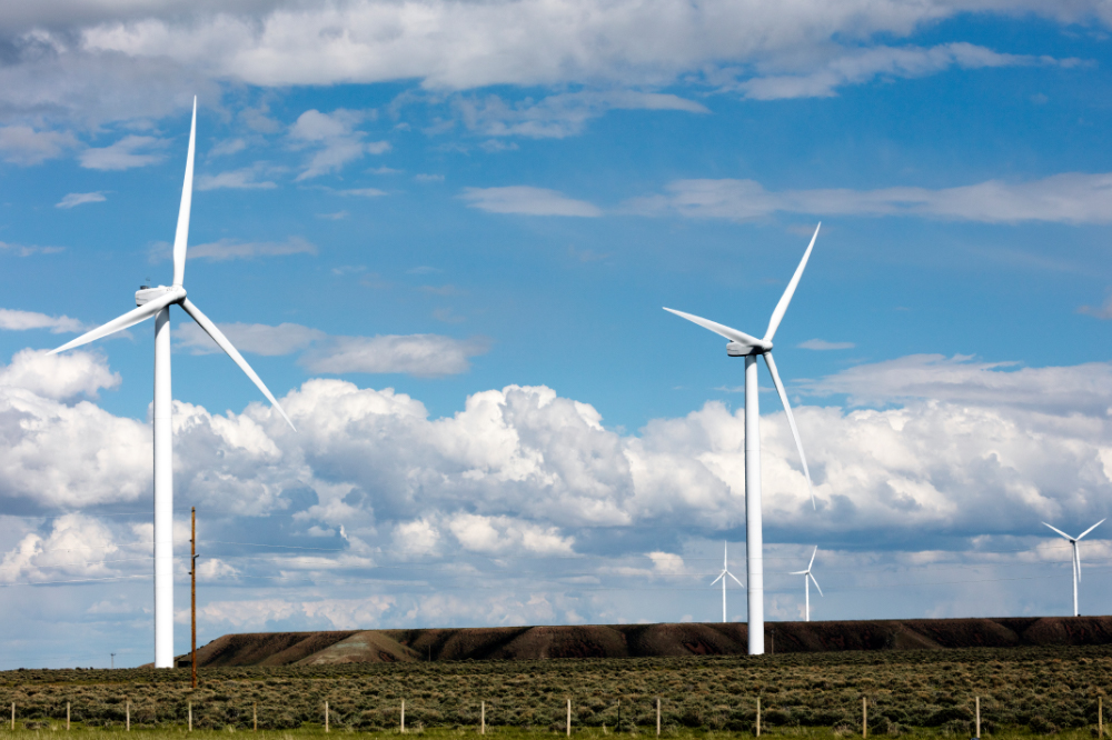 Wind power energy generators in a field against a blue sky
