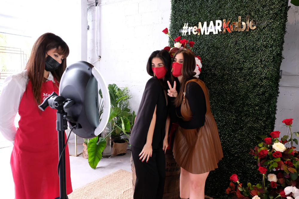 two women wearing masks and taking a photo together at an event photo booth