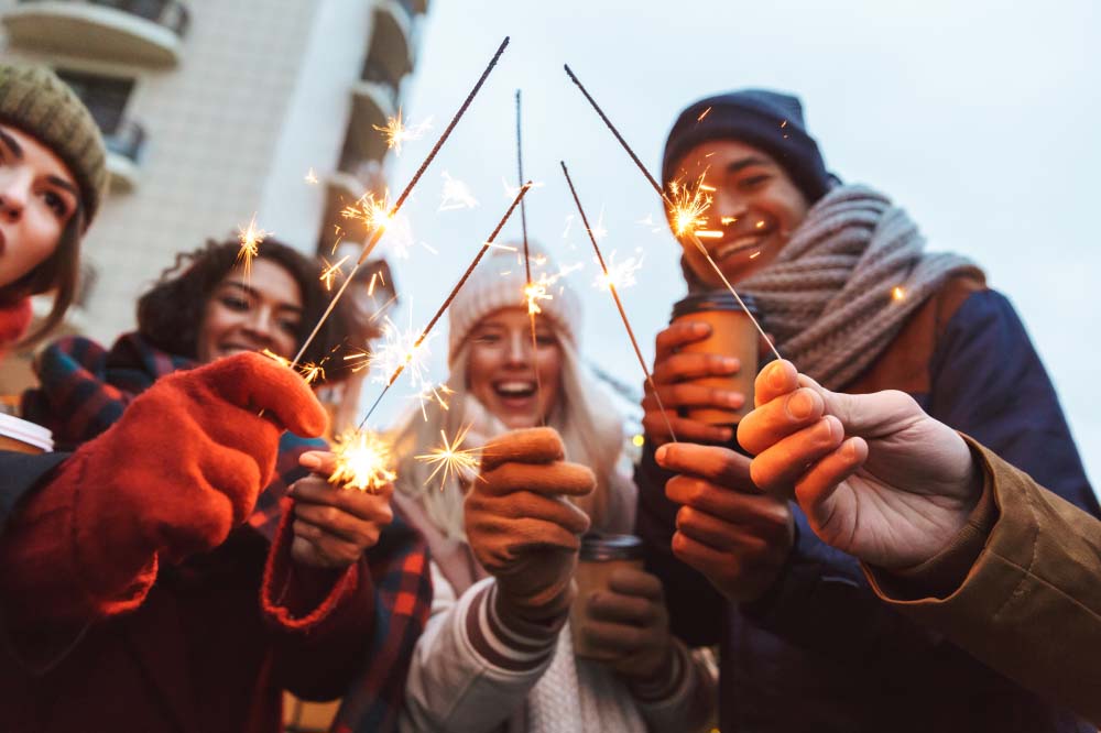 a group of friends lighting sparklers during the holidays