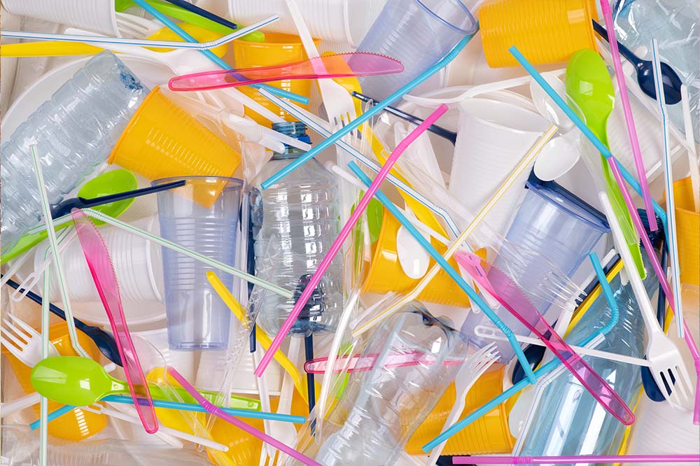 colorful plastic cutlery, cups and straws in a pile