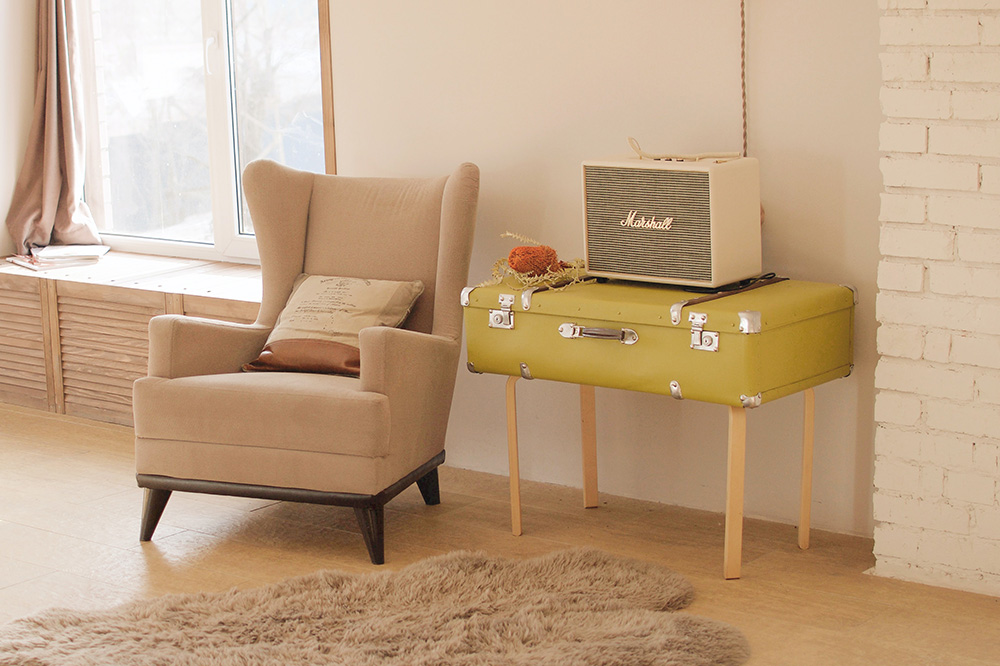 A mid-century modern chaise and a retro suitcase converted into a sidetable 