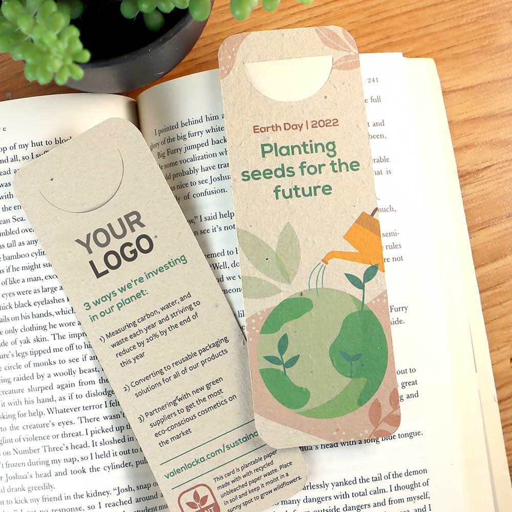 Earth Day bookmark design with rounded corners and a page slot sitting on an open book with a plant.