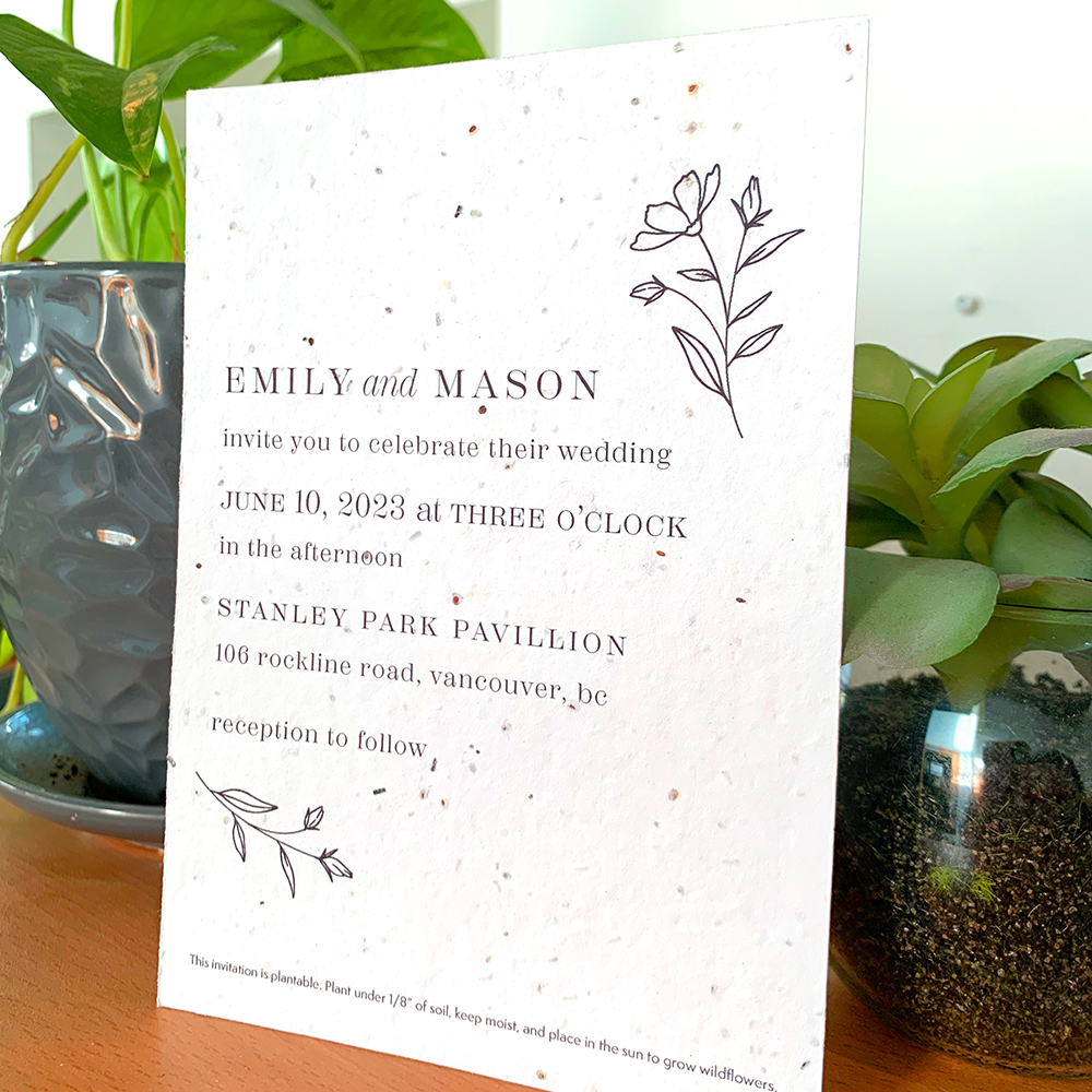 A plantable wedding invitation with a simple botanical design beside some plants