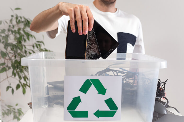A person putting old electronics into recycling bin