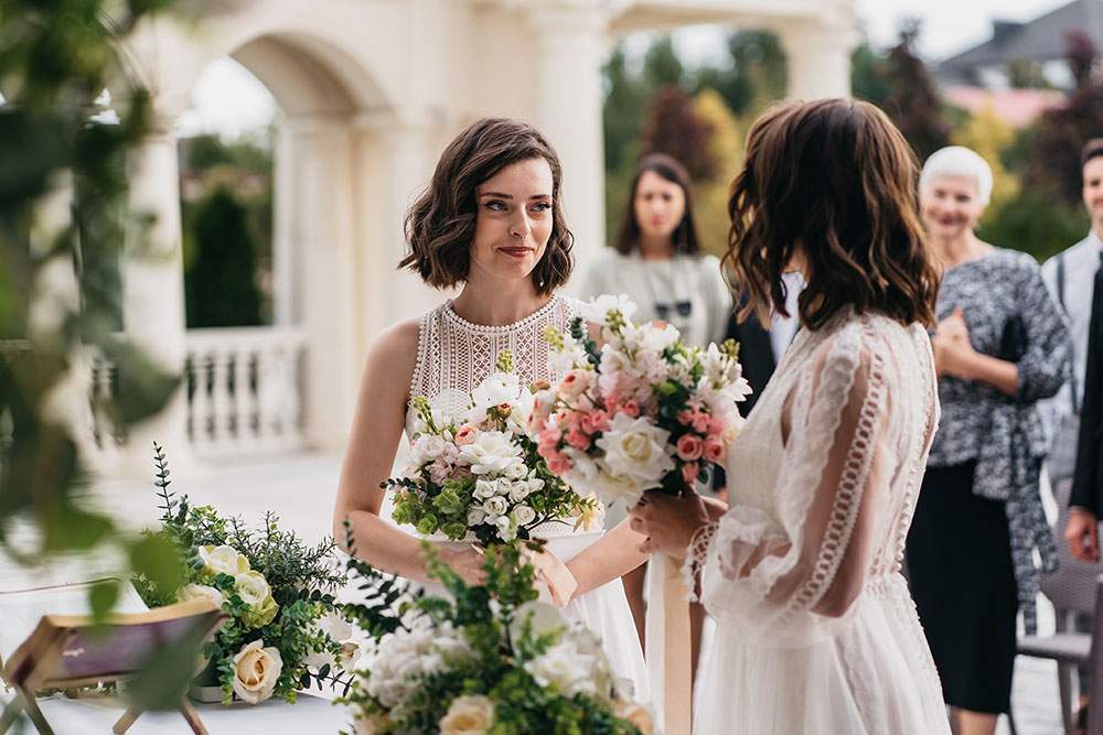 two brides standing at the alter looking lovingly at each other