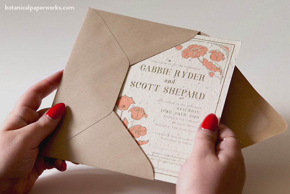 close up of a women pulling a wedding invitation out of an envelope