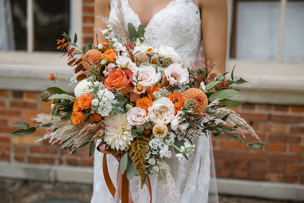 Close up of bride bouquet with orange and cream flowers. 