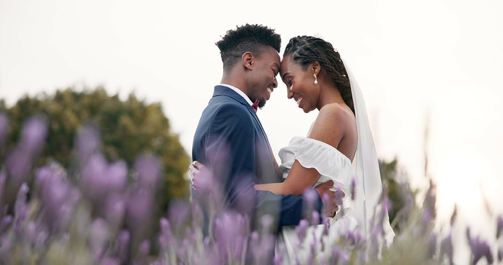 Bride and groom in a field with foreheads together